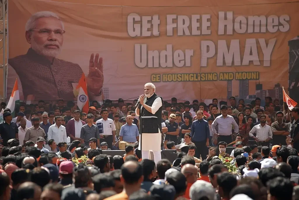 PM Awas Yojana Apply Online 2026 – Prime Minister Narendra Modi addressing a public rally with banner promoting free homes under PMAY housing scheme.